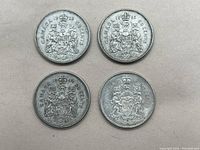 Top view of four Canadian silver fifty cent coins arranged in a grid on plain background.