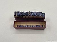 Numerical wood ink stamps arranged with digits visible, placed on and near the rectangular box.