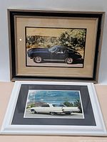 Photo showing two framed vintage car photos, one black sports car and one white classic car