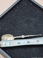 Small sterling silver decorative spoon laid next to ruler showing it measures about 3.5 inches