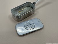 Metal sterilization case with lid closed, showing vented cross design on lid