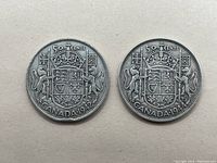 Two Canada 50 cent coins dated 1942 and 1944 showing the reverse side with the Canadian coat of arms.