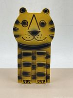 Front view of the vintage ceramic tiger piggy bank showing detailed black painted facial features and stripes on a yellow body.