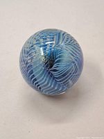 Top and side view of the spherical blue and white patterned glass paperweight