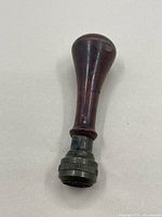 Front view of the vintage wooden handled ink stamp with rounded top and metal screw head.