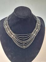 Front view of vintage 1960s rhinestone costume necklace on display bust showing bib style with multiple rhinestone strands.