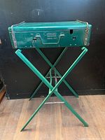 Green metal vintage Coleman Model 4M portable camping stove on foldable stand, showing overall condition and color.