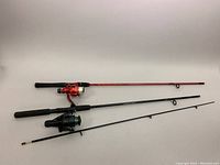 Overview of two fishing rods, one red and one black, both with reels and foam grip handles, showing length and general condition.