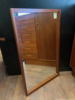 Front view of the rectangular teak framed mirror showing reflective surface and frame condition.