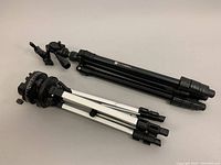 Two tripods lying down showing the folded legs and locking mechanisms, with the Platinum Series label visible on one.