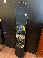 Front view of the black Rossignol K2 wide snowboard showing bindings and minor wear.