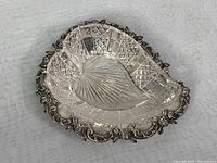 Heart-shaped silver repousse bowl with raised floral border and crystal insert with cut pattern inside silver frame
