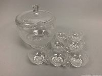 Front view showing punch bowl with lid and seven matching cups arranged in front.