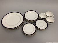 Full set of dinnerware including plates, cups, and saucers laid out on table showing quantity and design details.
