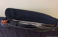 Wide angle shot showing the wooden golf clubs partially inside the closed black portable golf club bag