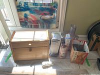 Wide view of the lot showing the bread box, food processor attachments in boxes, cream whipper on top, and serving tray leaning against the wall.