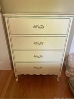Front view of the white vintage dresser showing four drawers with metal handles.