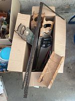Top view of box containing several hand saws and a wooden mitre box.