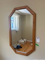 Full view of octagonal wood frame mirror mounted on wall showing dimensions and room reflection.