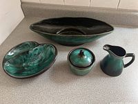 Full set of four Blue Mountain Pottery pieces: cream pitcher, sugar bowl with lid, divided serving bowl, and elongated serving bowl grouped on counter
