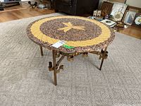 Photo of entire table showing terrazzo top and metal base with ornate supports and curved legs.
