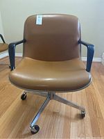 Front view of the vintage Steelcase rolling desk chair with brown faux leather upholstery and chrome base.