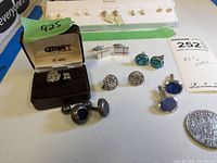 Overall grouping of ring, multiple cufflinks and earrings laid out on white background