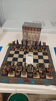 Full view of Civil War chess set on decorative chessboard with box of Civil War Journal VHS tapes behind it