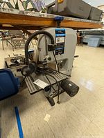 Full view of heavy metal bandsaw showing motor, table, blade tension and tracking controls.