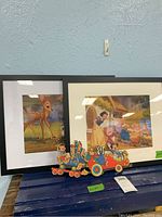 Two framed Disney prints with Snow White and Bambi, and two wood cutouts of Mickey Mouse and Pinocchio placed in front.