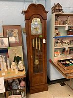 Full view of the Ridgeway grandfather clock placed near some shelves and figurines on the side