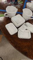 Overview of the 6-piece milk glass set showing trays and cream and sugar containers on a wooden table.
