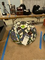 Top angled view showing the stained glass dome lamp shade with hummingbird and flower design, metal vented cap at top.