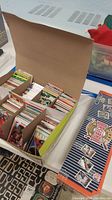 Open box showing numerous sports cards organized inside in multiple rows and dividers.