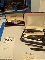 Croton Aquamatic watch in original box alongside a case with multiple shirt collar stays for men's shirts.