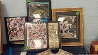 Four framed plaques related to New York Yankees baseball championships and Alex Rodriguez milestone home run achievement shown together on a table