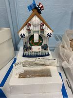 Full front view of the New York Yankees cuckoo clock placed on its white Styrofoam packaging with certificate and tag visible.
