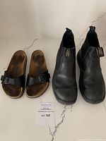 Birkenstock Madrid sandals next to Blundstone ankle boots on light marbled floor.