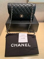 Front view of the Chanel purse placed on top of its box and dustbag
