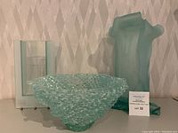 Three pieces together: fused glass bowl front center, frosted slab panel vase left, draped-form vase right