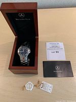 Opened Mercedes-Benz wooden presentation box containing watch, instruction card, and hang tags