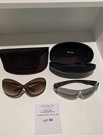 Both pairs of sunglasses with their respective cases shown on a white surface