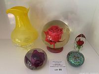 Lot overview with yellow vase on left and acrylic rose paperweights and millefiori paperweight on right