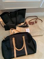 All three bags displayed: black Saint Laurent tote with zip pouch, Danier duffel bag, and Longchamp foldable carry bag