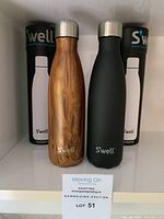 Pair of Swell bottles with packaging, showing faux wood and matte black finishes