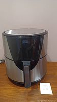 Front view of Ultima Cosa air fryer model TXG-FS075A showing stainless steel body with black plastic top and handle.