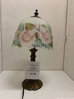 Table lamp with ribbed glass shade painted with floral reverse hand painting, showing the full lamp standing on a flat surface.