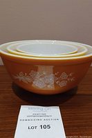 Side view of three nested Pyrex mixing bowls in Butterfly Gold pattern showing size differences and exterior designs.