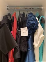 Five dresses hanging on metal rod inside wardrobe