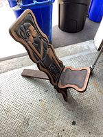 Photo showing angled view of a wooden chair with carved figure on the backrest